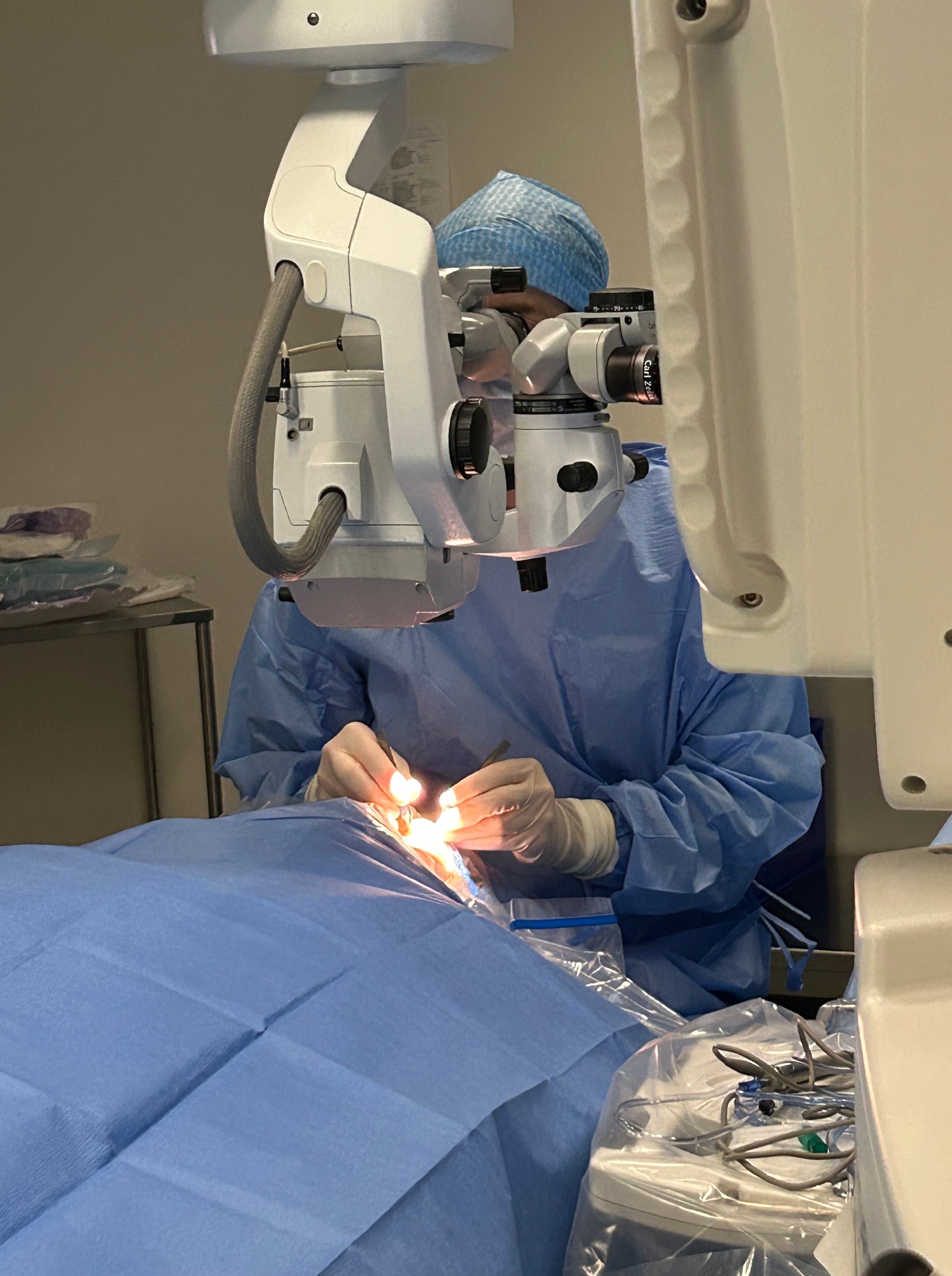 Chirurgien réalisant une opération de la cataracte, avec un microscope opératoire, dans un environnement stérile.